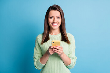 Wall Mural - photo portrait of happy woman holding phone in two hands isolated on pastel blue colored background