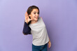 © luismolinero - Little girl isolated on purple background listening to something by putting hand on the ear