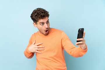 Wall Mural - Caucasian man isolated on blue background making a selfie