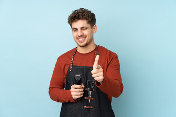 Wall Mural - Hairdresser caucasian man isolated on blue background points finger at you