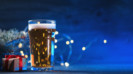 Wall Mural - A glass of light beer on the table, a glowing blue background with a garland. Holiday festival