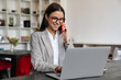 © Drobot Dean - Beautiful joyful woman talking on cellphone while working with laptop