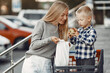© hetmanstock2 - Mother is driving in a trolley. Family in a parking near a supermarket.