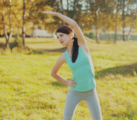 Fitness woman doing exercises on the grass in sunny summer park