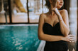 © BGStock72 - Beautiful young woman standing by the window at swimming pool