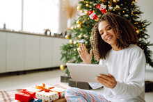 Christmas Online Holiday. Happy Woman Having Video Call With Their Family Or Friends. Young Woman Uses A Digital Tablet Near Decorated Festive Tree At Home. Virtual Meeting. Covid-2019.
