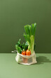 © Maki Company Limited/Stocksy - White mesh shopping bag with red tomatoes, bow and green cucumbers on white background. Top view, flat lay, Zero waste, eco friendly concept.