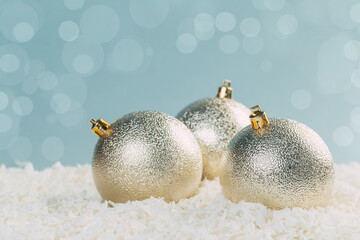 silver Christmas balls in white snow on a blue background with bokeh lights. happy new year card