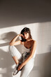 © Marc Bordons/Stocksy - Portrait of a serious girl sitting on a column with a warm natural light on the side.