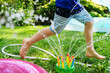 © jamie grill photography/Stocksy - Little Boy Running Through Sprinkler in the Backyard