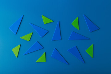 Wall Mural - Abstract duotone flat lay with green and blue triangles on blue background