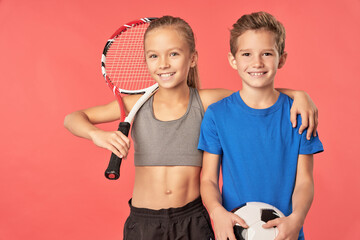 Adorable sporty girl and boy standing against red background