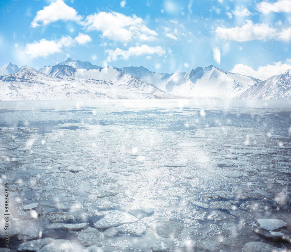 frozen mountain lake in winter with broken ice cracks. Large chunks of ...