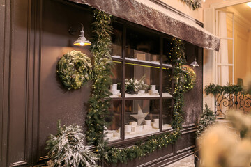 Wall Mural - Vintage street cafe window. French cafeteria showcase with Christmas fir wreath covered with snow. Facade of street retro restaurant. Winter cafe decoration. Copy space. Christmas concept. Postcard