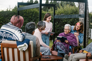 Wall Mural - Mexican grandmother and family reading a book in a backyard outside home in Mexico city