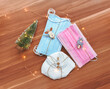 Pink and blue surgical masks and white FFP2 masks decorated as presents or gifts with a Christmas tree with lights on wooden background. Safe Christmas during COVID-19 pandemic concept or illustration