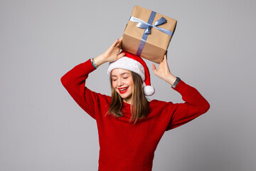 Wall Mural - Happy pretty young woman holding gift box isolated over gray background