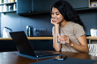 © F8  \ Suport Ukraine - Smiling afro woman with glass of water using laptop in the kitchen at home