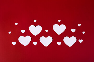 Sticker - Shot of white big and small paper hearts arranged on the red background, a Saint Valentine's theme