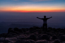 Silhouette Man In The Back With Arms Open Standing On Viewpoint At Nodular Stones Mountain Peak Or Lan Hin Poom During Sunset, Phu Hin Rong Kla National Park In Phitsanulok, Thailand, Freedom  Concept