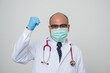 © Chanakon - Asian bald Doctor in white coat, stethoscope, blue glove wearing face mask erect his fist feel power look into camera.isolated on white background.