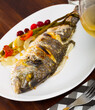 Delicious grilled gilthead bream (dorada) with lemon, baked vegetables and fresh berries..