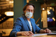 © Svitlana - Focused gentleman in respiratory mask studying some papers