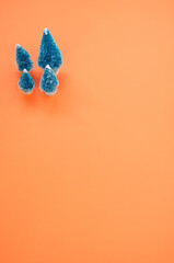 Wall Mural - Vertical shot of Christmas pine figurines on orange surface for a copy space