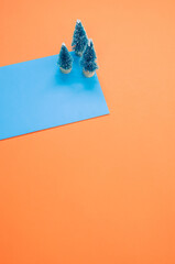 Wall Mural - Vertical shot of Christmas pine figurines on blue and orange background for a copy space