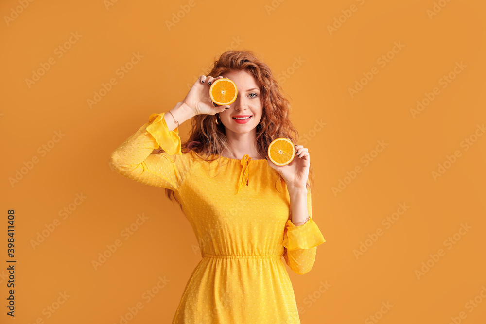 Beautiful young woman with cut orange on color background