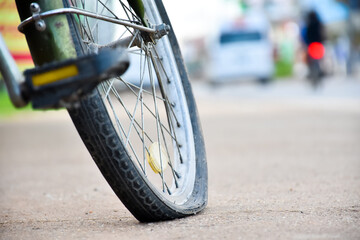 Rear wheel of bike which is flat and parked on the pavement beside the road.