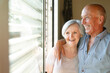 © alex.pin - bellissima coppia di anziani si abbraccia felice vicino alla finestra del salotto