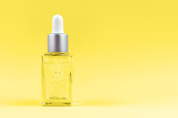 Demonstrating trendy color of 2021 - Yellow. Glass transparent mockup bottle with dropper with cosmetic serum, oil, on pastel pink background.