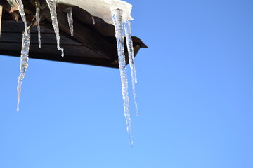 icicle on roof, spring thaw. icicles against blue sky. early Spring season, winter end.