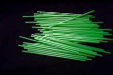 A Row Of Green Plastic Straws Isolated On A Black Background.