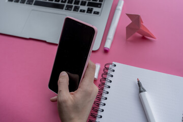 Canvas Print - High angle shot of a laptop, a cellphone, and writing tools on a pink surface