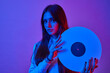© wertinio - Disco woman portrait holding a retro vinyl with 80s music on neon light background.