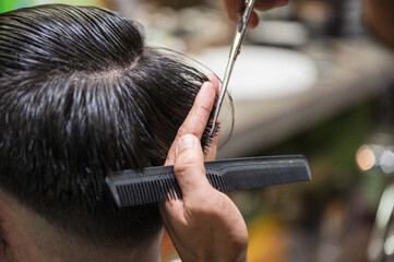 Barber cutting haircut the client hair with scissors and comb