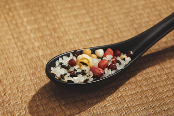 Sticker - Closeup of a rice mixe with nuts in a black spoon on a beige surface