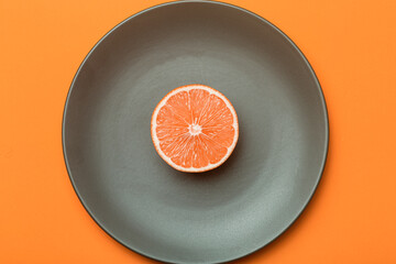 Wall Mural - Red orange (or grapefruit) against empty gray plate background. Minimal food and oranges art. Diet and vitamins concept.