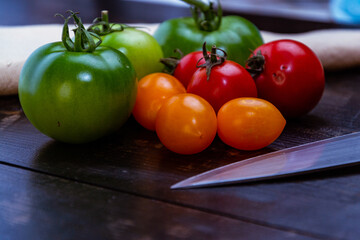 Sticker - Closeup shot of ripe and unripe tomatoes with knife and napkin on a wooden table