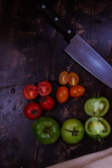 Canvas Print - Vertical shot of sliced ripe and unripe tomatoes with knife and napkin on a wooden table