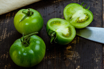 Wall Mural - Closeup shot of sliced green tomatoes with knife and napkin on a wooden