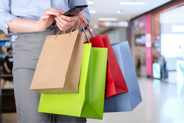 Asian woman shopping holding shopping bag and mobile phone at shopping center. Consumerism, sale and people online concept.