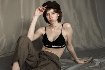 portrait of a young woman  in in trousers and a top. Model with hat and short hair. Natural clean face