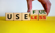 Useful or useless symbol. Male hand turns cubes and changes the word 'useless' to 'useful'. Beautiful yellow table, white background. Business and useful or useless concept. Copy space.