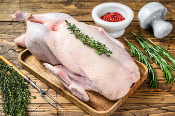 Raw whole farm duck with herbs. wooden background. Top view