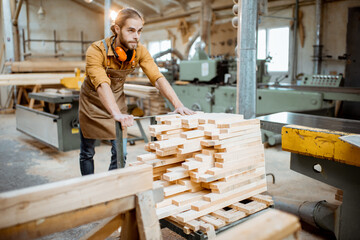 Wall Mural - Carpentry worker pushing cart full of wooden planks at the joinery warehouse