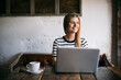 © Andr√©s Benitez/Westend61 - Smiling woman looking away while using laptop in cafe
