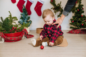 Little cute boy in a red plaid shirt near little Christmas trees. Christmas mood